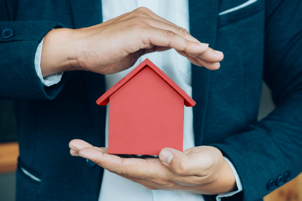 business man hand hold the house model saving small house.